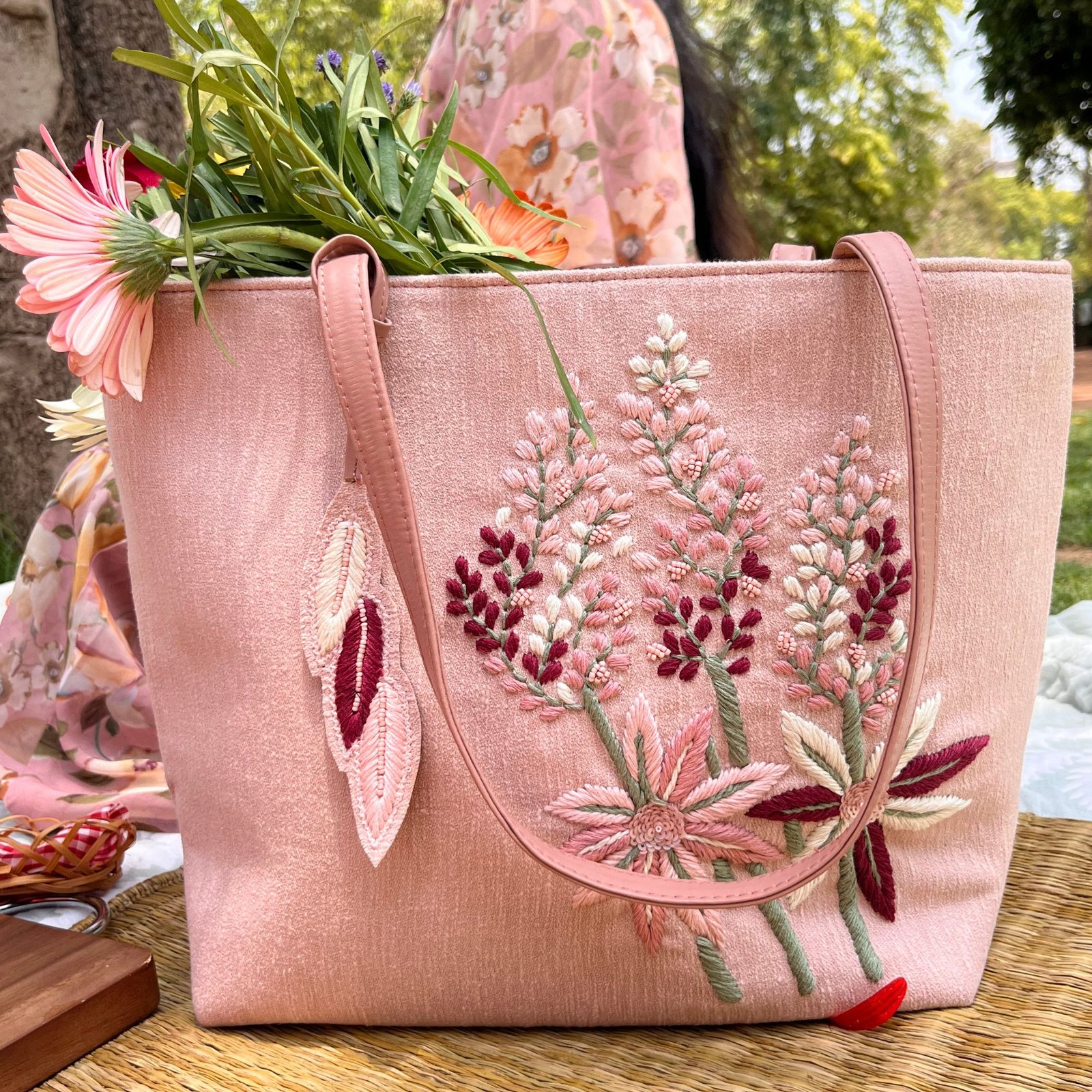 Blush pink handcrafted tote bag with floral embroidery styled outdoors Blush pink handcrafted tote bag with floral embroidery styled outdoors
