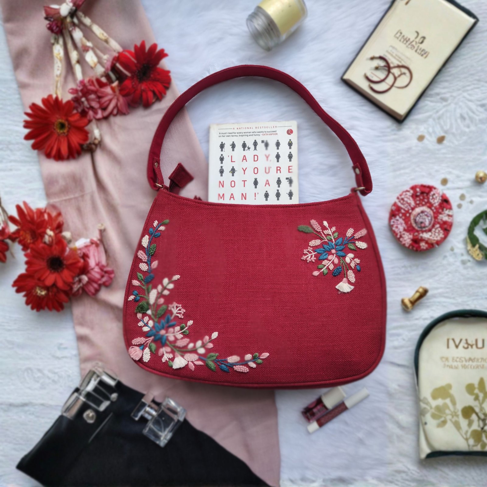 Cherry red handcrafted hobo bag with floral embroidery flat lay Cherry red handcrafted hobo bag with floral embroidery flat lay