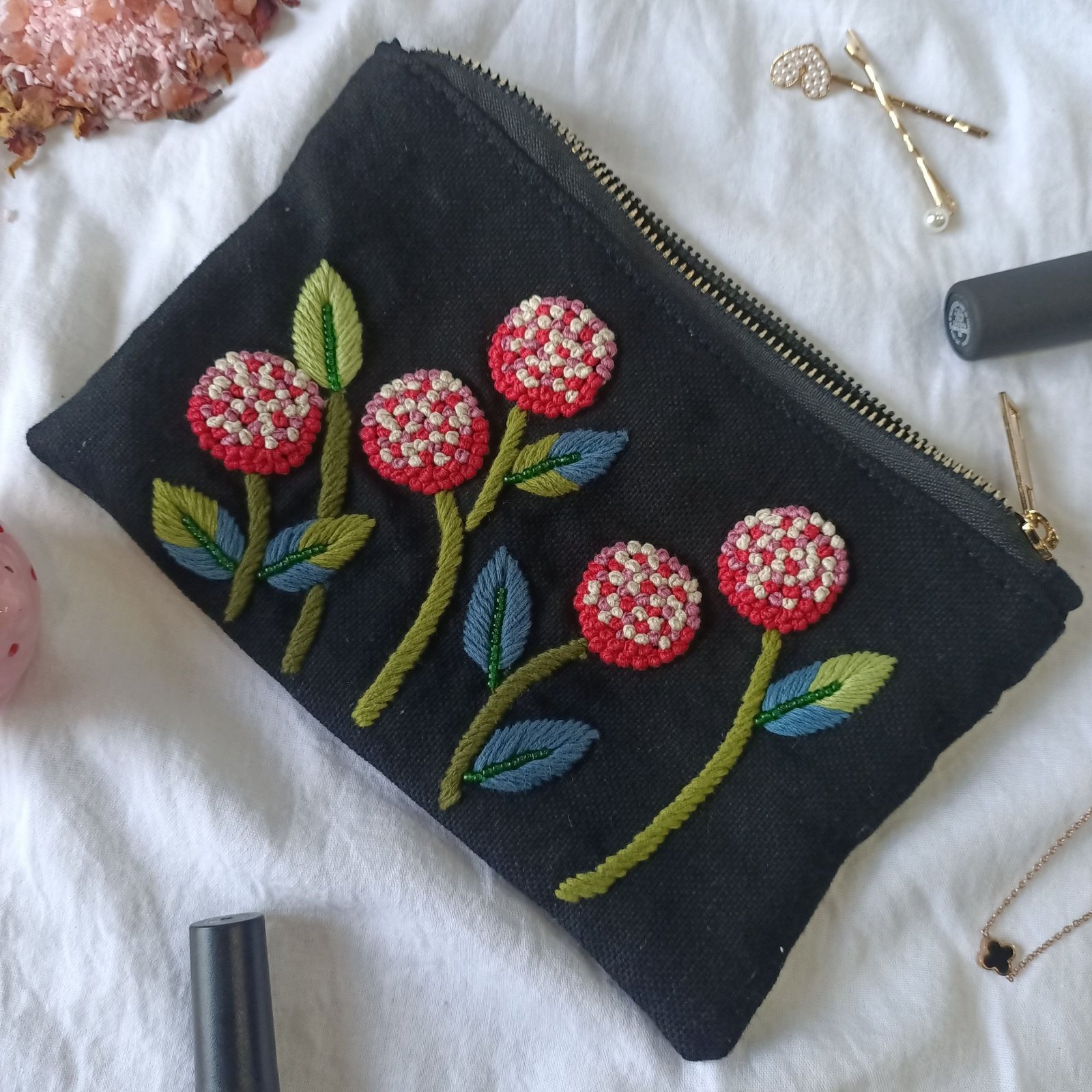 Small essential pouch with red floral embroidery on black fabric Small essential pouch with red floral embroidery on black fabric